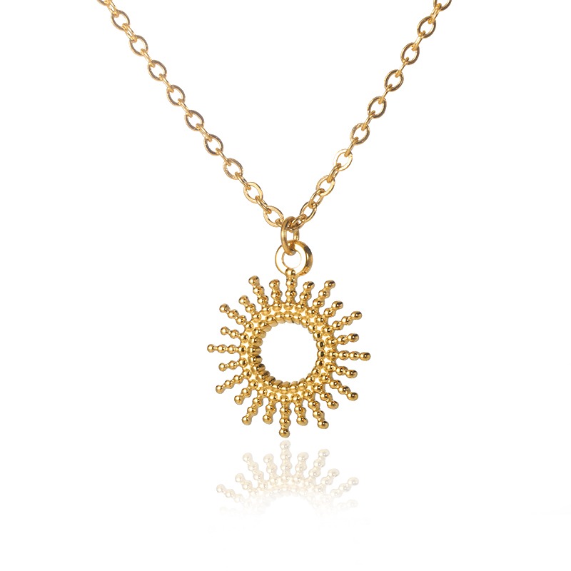 Un collier doré en forme de soleil au milieu creux sur fond blanc.