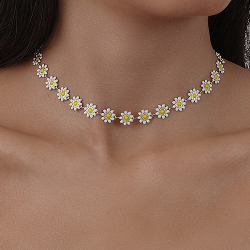 Le cou d'une femme avec un collier ras de cou en fleurs de marguerite.