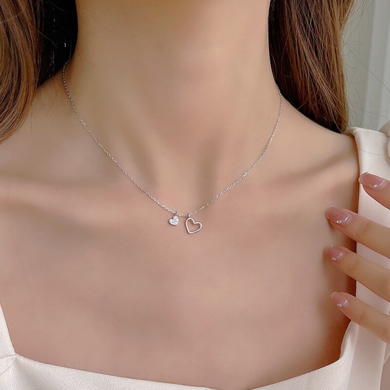 Un collier argenté en coeur autour d'un cou.