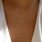 Collier mauvais oeil chaîne fine métal pendentif strass bleu porté par une femme